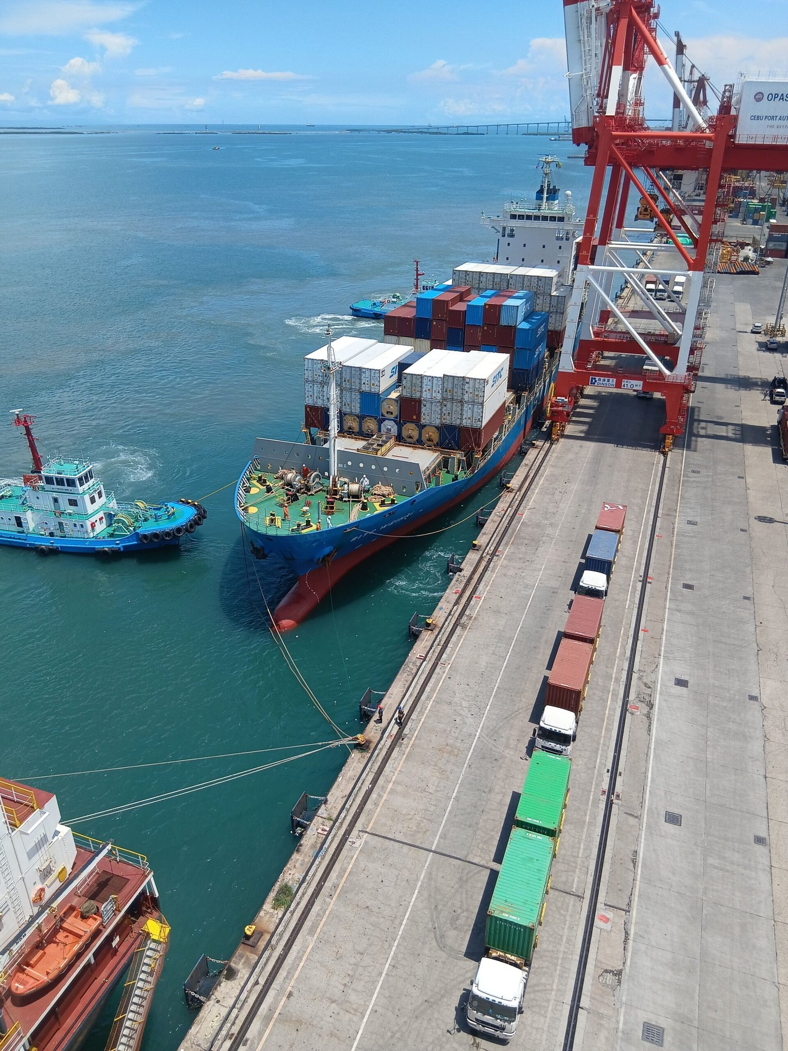 Aerial view of a container ship docking at a busy maritime port in the Philippines.